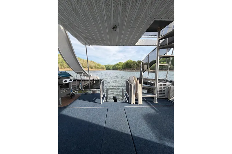 Slide: The Image of Houseboat deck view with spiral staircase, overlooking serene lake and lush greenery. Sunstar 16x65, 2000. - 32