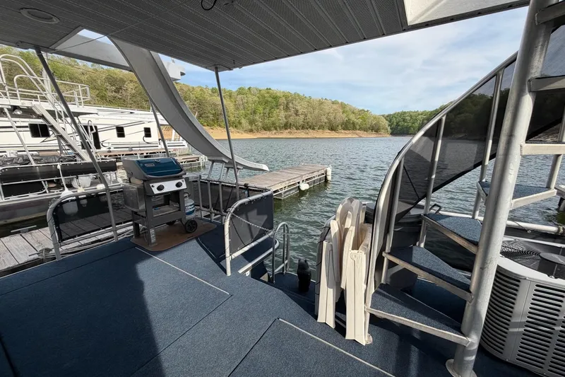 Slide: The Image of Houseboat deck with grill and spiral staircase, Sunstar 16x65, 2000 model, docked by a scenic lake. - 36
