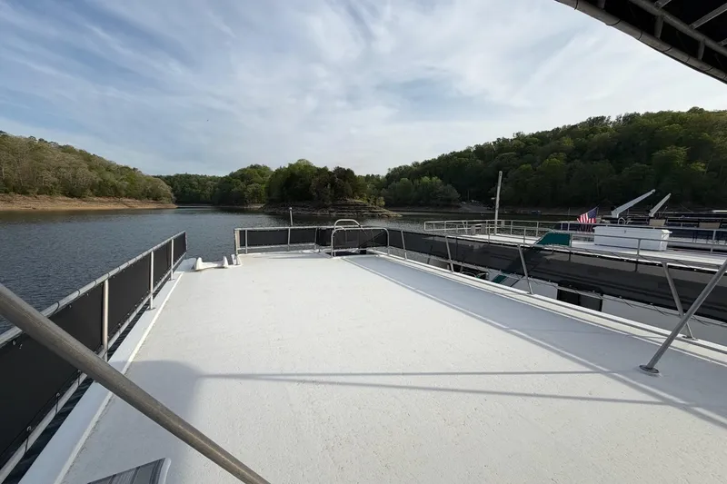 Slide: The Image of Sunstar 16x65 houseboat deck overlooking serene lake and lush green shoreline, 2000 model. - 48