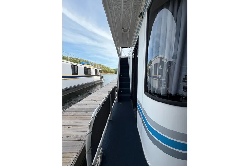 Slide: The Image of Side view of a 2000 Sunstar 16x65 houseboat docked by a wooden pier. - 5
