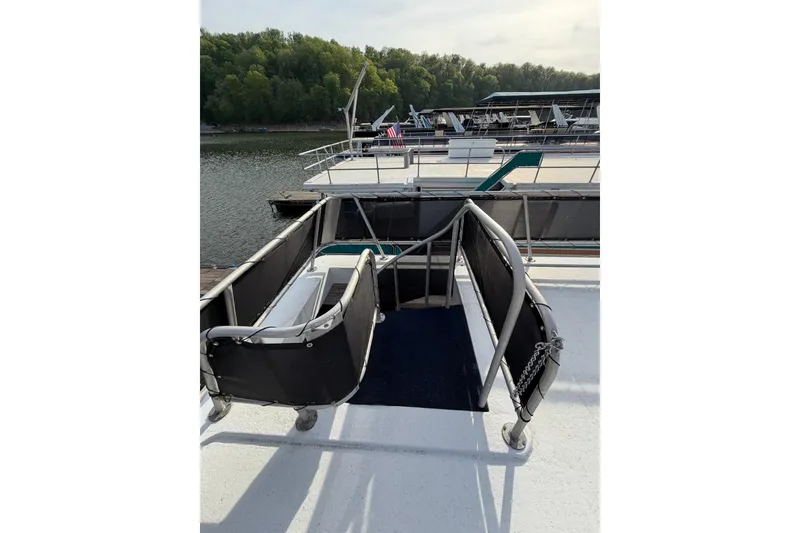 Slide: The Image of Sunstar 16x65 houseboat deck with railing, docked on a serene lake, 2000 model. - 53