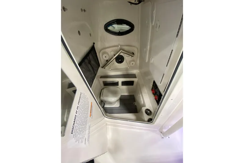 Slide: The Image of 2024 Sailfish 242 CC boat interior with compact marine toilet and storage. - 17