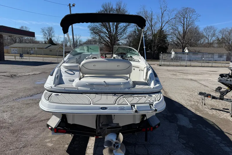 Slide: The Image of 2007 Crownline 240 EX boat with canopy, parked on pavement under clear blue sky. - 3