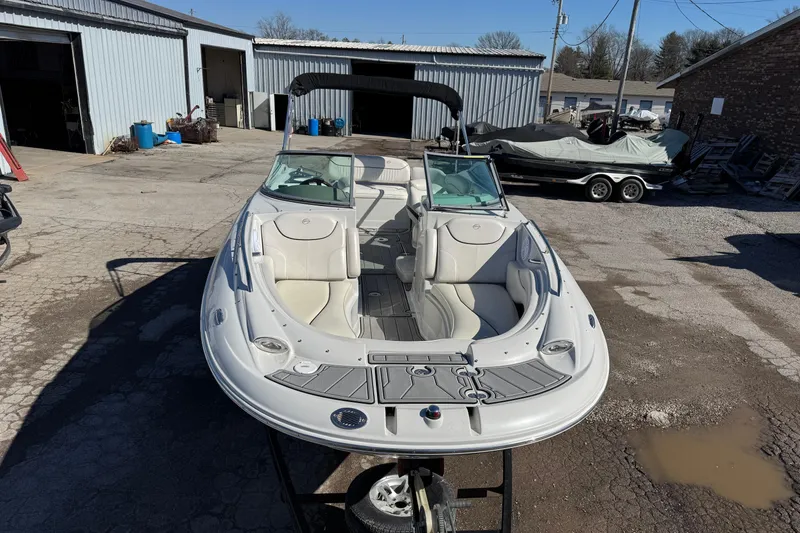 Slide: The Image of 2007 Crownline 240 EX boat in a storage yard, showcasing sleek design and spacious seating. - 7