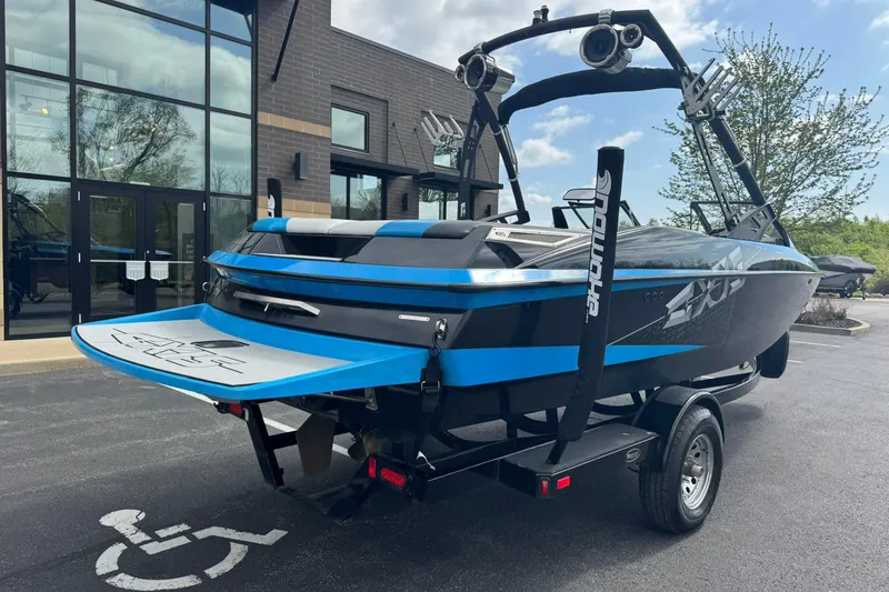Slide: The Image of 2011 Axis A20 boat with blue accents on a trailer, parked near a building. - 3