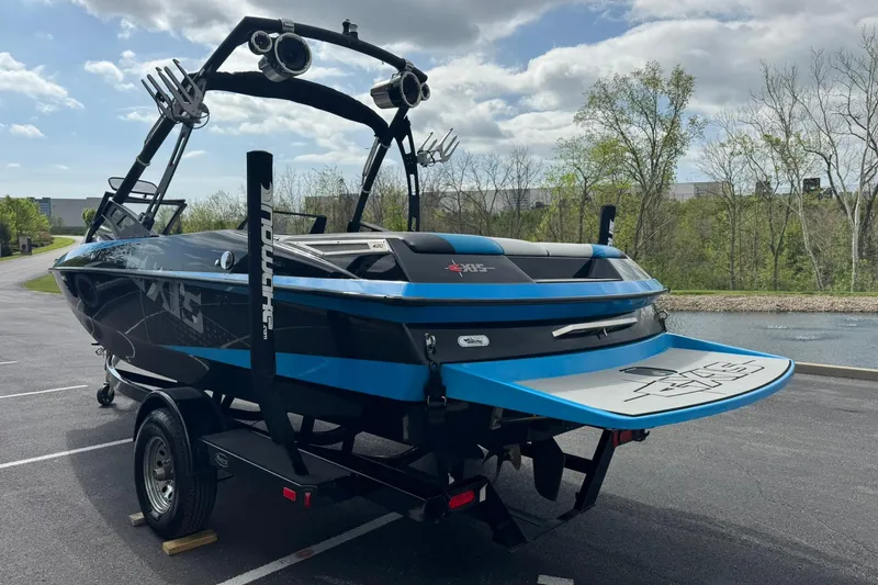 Slide: The Image of 2011 Axis A20 boat on trailer, parked outdoors with trees and cloudy sky. - 5