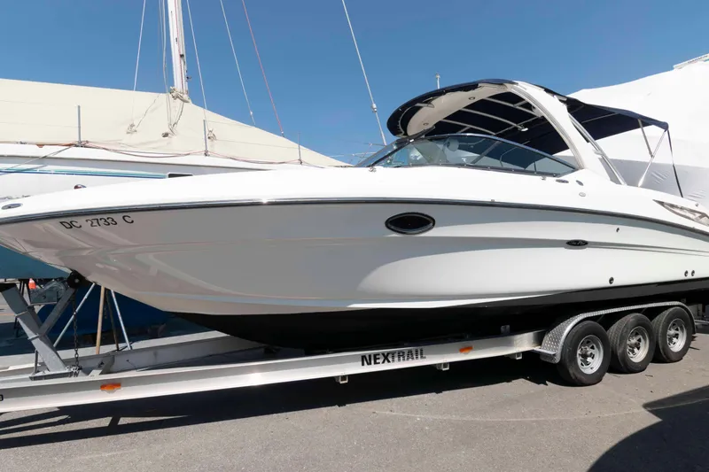 The Image of 2009 Sea Ray 300 SLX boat on trailer, displayed outdoors under clear blue sky. - 0