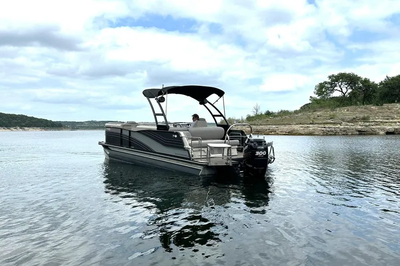 Slide: The Image of 2018 Harris Grand Mariner 250 pontoon boat on a serene lake under a cloudy sky. - 11