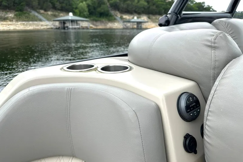 Slide: The Image of 2018 Harris Grand Mariner 250 boat interior with cup holders and control panel by a lake. - 34