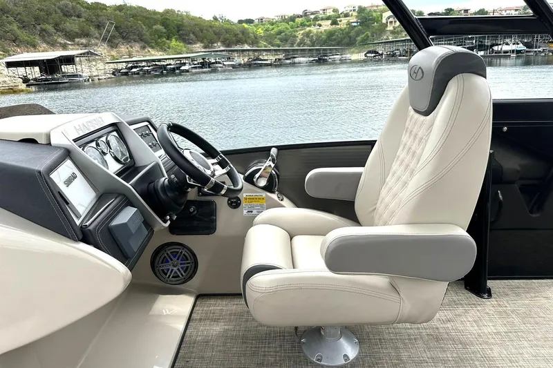 Slide: The Image of Captain's chair and dashboard of 2018 Harris Grand Mariner 250 boat by a lake. - 39