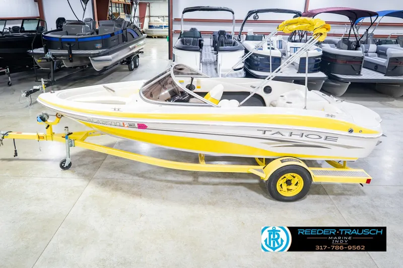 The Image of Yellow 2005 Tahoe Q4 boat on trailer in showroom with other boats. - 2