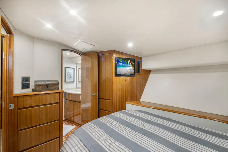 Slide: The Image of Luxurious 2009 Viking 50 Convertible yacht bedroom with wood accents and modern amenities. - 24
