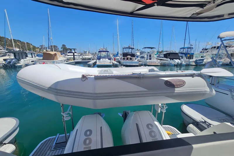 Slide: The Image of 2021 Jeanneau NC Weekender 895 docked, featuring a dinghy and twin outboard motors. - 14
