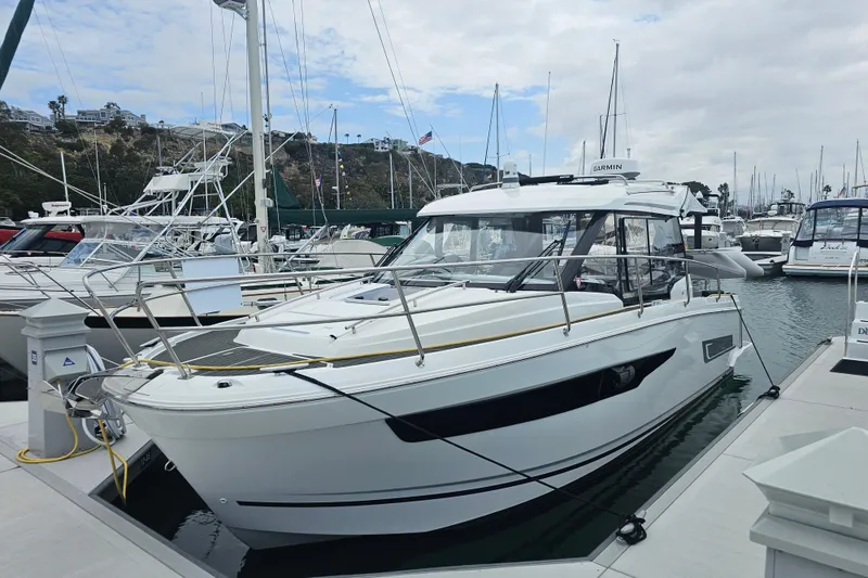 Slide: The Image of 2021 Jeanneau NC Weekender 895 docked at a marina, surrounded by other boats. - 2