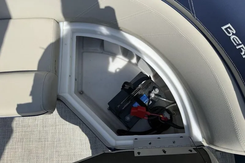 Slide: The Image of Battery compartment of a 2022 Berkshire 24RFX LE boat, featuring beige seating and storage. - 28