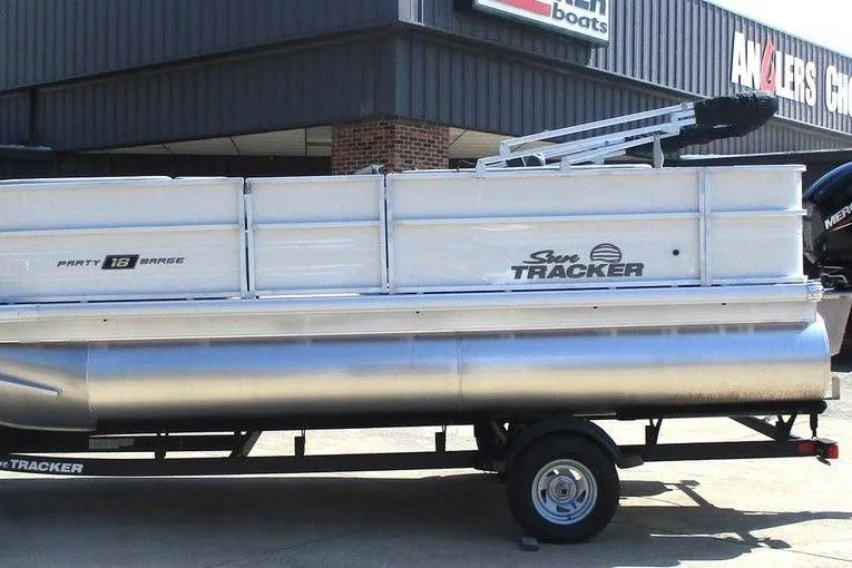 The Image of 2026 Sun Tracker Party Barge 18 DLX pontoon boat on trailer outside dealership. - 1
