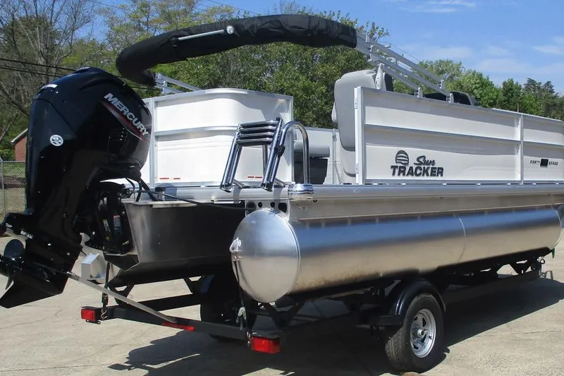 Slide: The Image of 2026 Sun Tracker Party Barge 18 DLX pontoon boat on trailer, featuring Mercury outboard motor. - 6