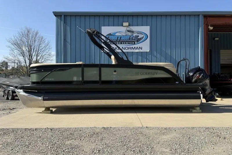 The Image of 2026 Godfrey Monaco 235 SB pontoon boat displayed outside a marine center. - 1