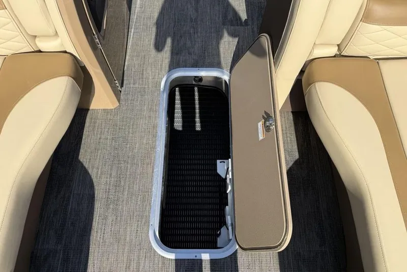 Slide: The Image of 2026 Godfrey Monaco 235 SB boat interior with open storage compartment and beige seating. - 11