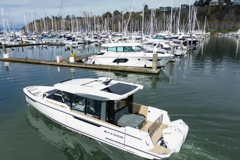 Slide: The Image of 2026 Saxdor 400 GTC boat cruising in a marina with numerous docked yachts. - 10