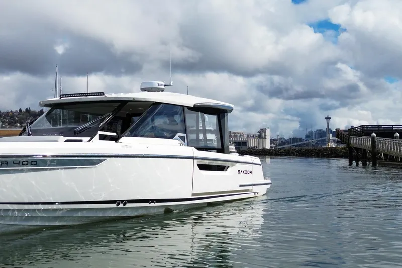 Slide: The Image of 2026 Saxdor 400 GTC boat cruising near a city skyline under cloudy skies. - 3