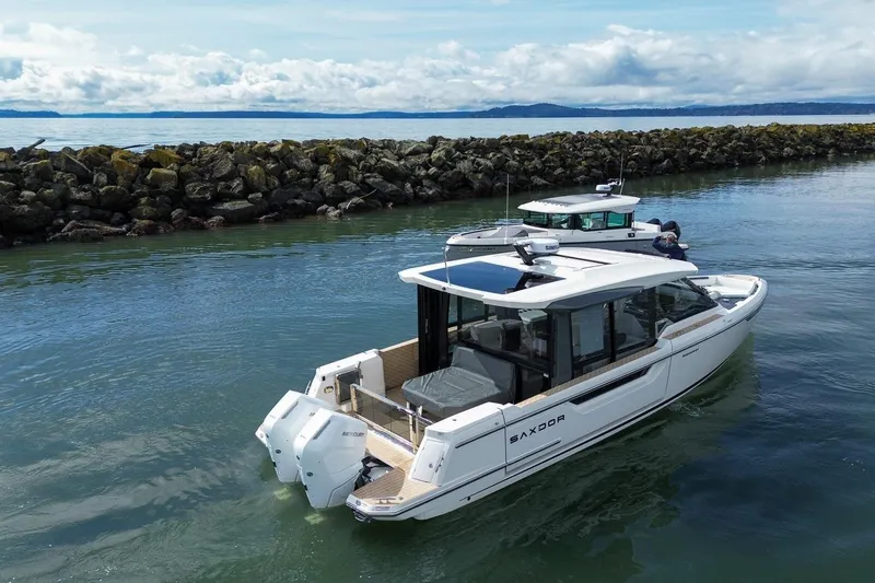 Slide: The Image of 2026 Saxdor 400 GTC boat cruising near rocky shoreline under cloudy sky. - 7