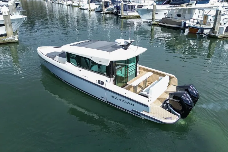 Slide: The Image of 2026 Saxdor 320 GTC boat docked in marina, featuring sleek design and twin Mercury engines. - 2