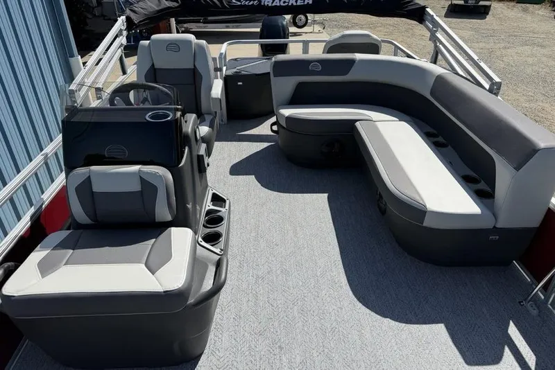Slide: The Image of 2026 Sun Tracker Bass Buggy 18 DLX pontoon boat interior with gray seating and steering console. - 11