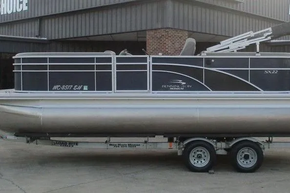The Image of 2018 Bennington 22SSRXP pontoon boat on trailer, parked outside a building. - 1