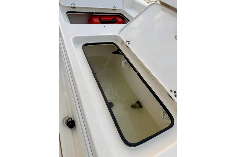 Slide: The Image of Open storage compartments on a 2009 ShearWater 2400Z boat, featuring a livewell and red container. - 28
