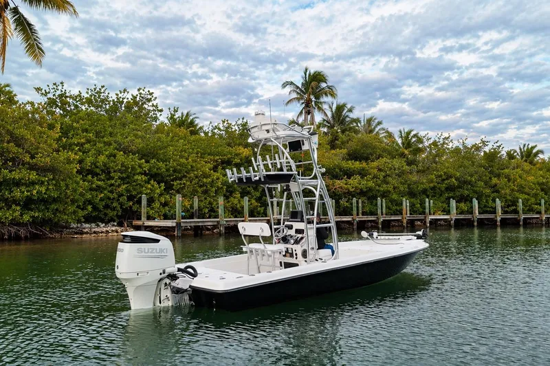 Slide: The Image of 2009 ShearWater 2400Z boat with Suzuki engine on calm water, surrounded by lush greenery. - 9