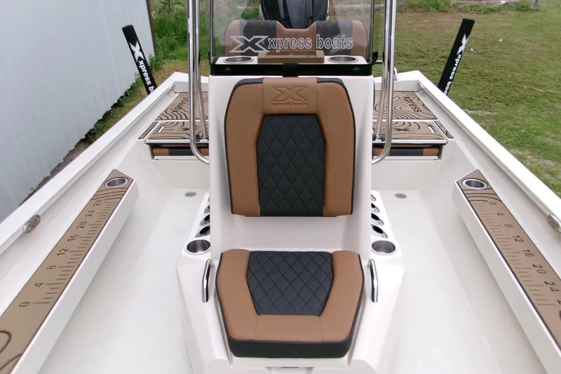 Slide: The Image of 2026 Xpress H22B Bay boat interior with brown and black seating, featuring built-in cup holders. - 13