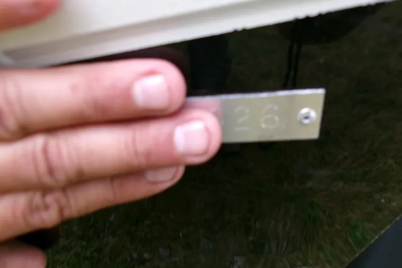 Slide: The Image of Hand holding a metal plate with "26" on a 2026 Xpress H22B Bay boat. - 5