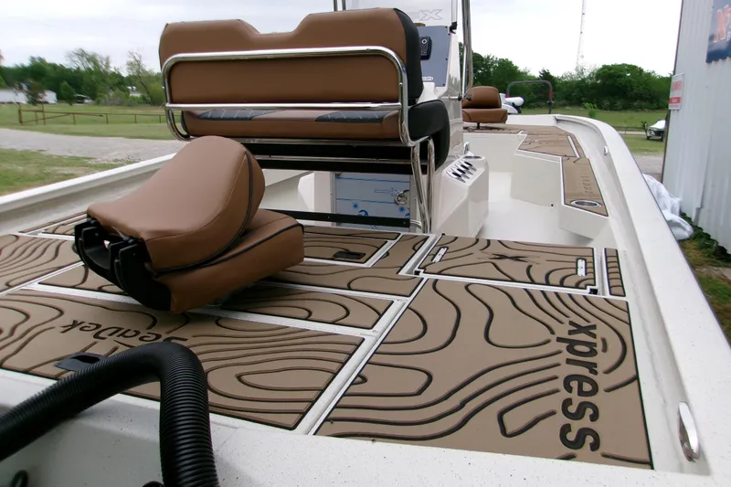 Slide: The Image of 2026 Xpress H22B Bay boat interior with brown seating and custom flooring design. - 7