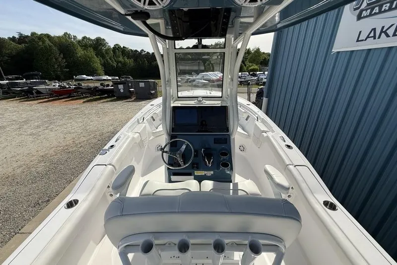 Slide: The Image of 2026 Tidewater 232 LXF boat interior with steering console and seating, parked outdoors. - 22
