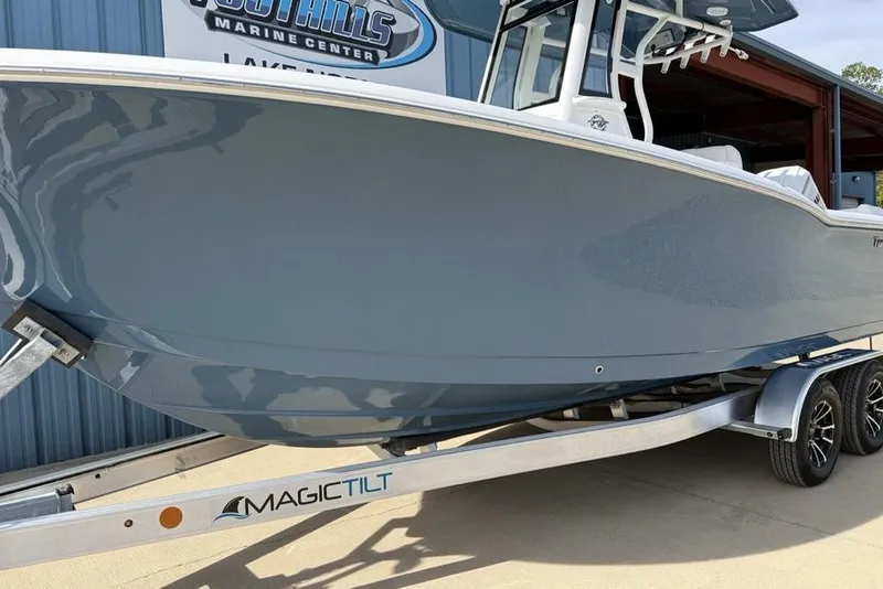 Slide: The Image of 2026 Tidewater 232 LXF boat on Magic Tilt trailer at marine center. - 5