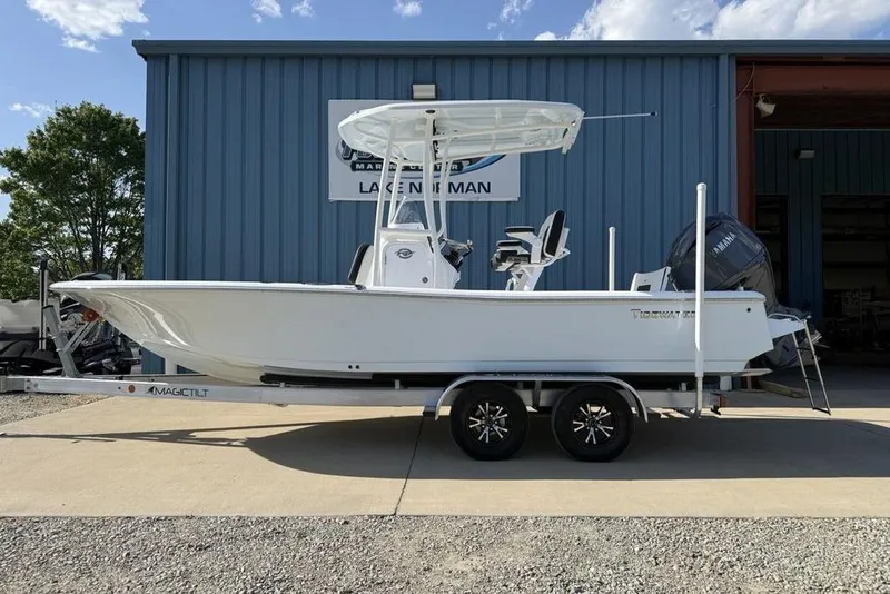 Slide: The Image of 2025 Tidewater 2210 Carolina Bay boat on trailer, parked outside a blue building. - 7