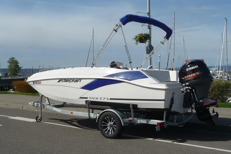 The Image of 2022 Starcraft SVX 171 OB boat on trailer with Yamaha outboard motor, parked near marina. - 0