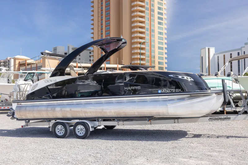 The Image of 2016 Harris Crowne 250 pontoon boat with luxurious seating and sleek design on a trailer. - 0