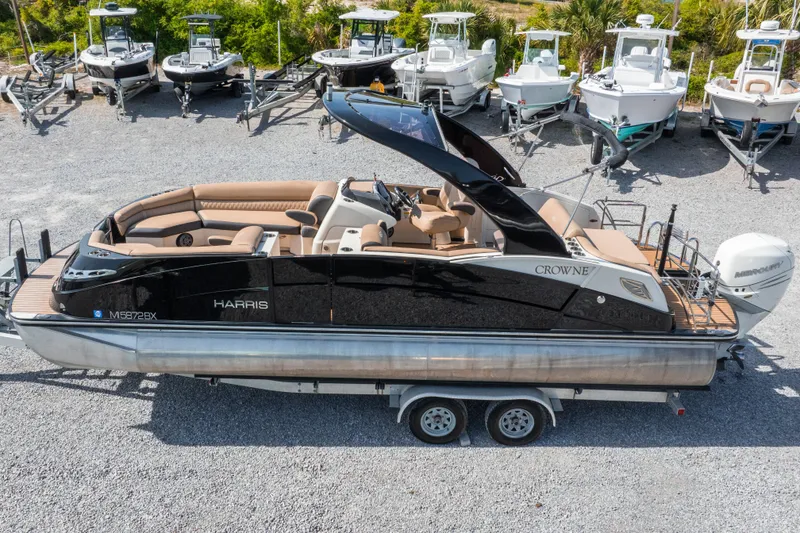 Slide: The Image of 2016 Harris Crowne 250 pontoon boat on trailer, surrounded by other boats. - 10