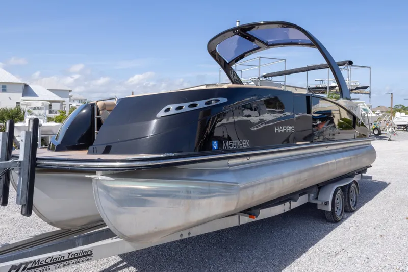 Slide: The Image of 2016 Harris Crowne 250 pontoon boat on trailer, sleek black design. - 16