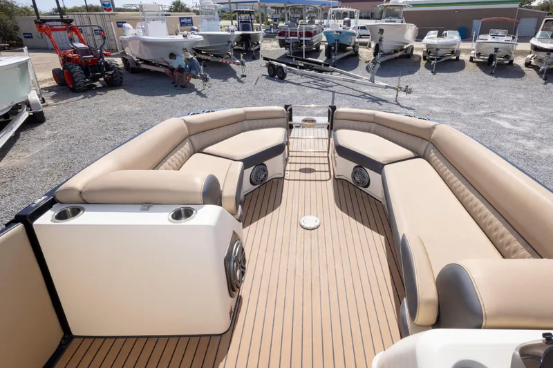 Slide: The Image of 2016 Harris Crowne 250 pontoon boat with beige seating and wood-style flooring in a boatyard. - 30