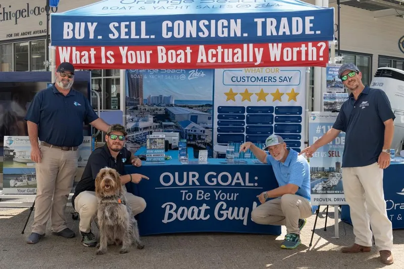 Slide: The Image of Group at boat sales booth with promotional banners and a dog. - 7