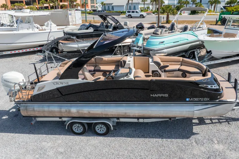 Slide: The Image of 2016 Harris Crowne 250 pontoon boat on trailer, parked in marina lot. - 9