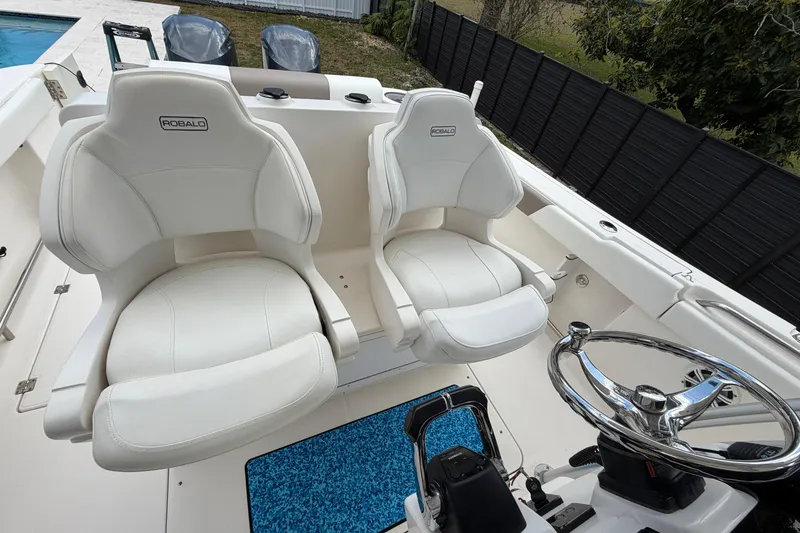 Slide: The Image of 2015 Robalo R300 Center Console boat interior with dual white captain's chairs and steering wheel. - 18