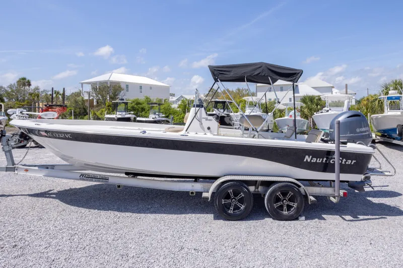 Slide: The Image of 2017 NauticStar 2400 Sport boat on trailer, parked outdoors under clear sky. - 11