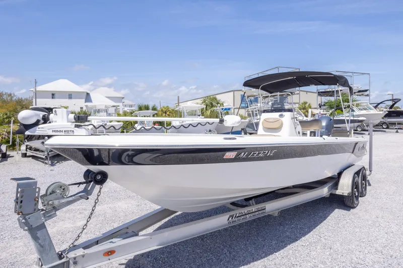 Slide: The Image of 2017 NauticStar 2400 Sport boat on trailer, parked outdoors under clear blue sky. - 12