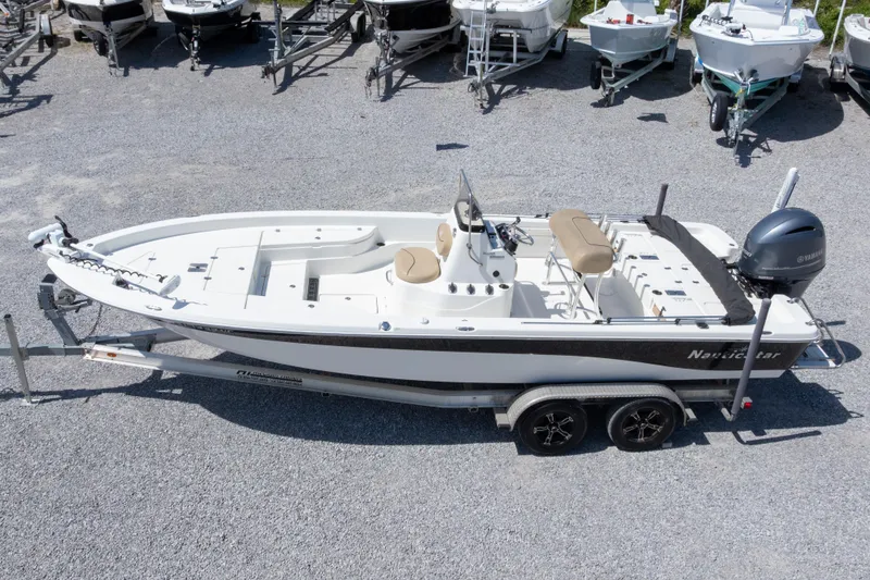 Slide: The Image of 2017 NauticStar 2400 Sport boat on trailer, parked among other boats. - 2