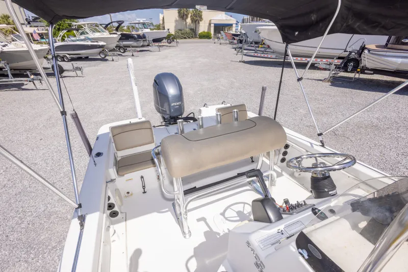 Slide: The Image of 2017 NauticStar 2400 Sport boat interior with steering wheel and seating, parked outdoors. - 22