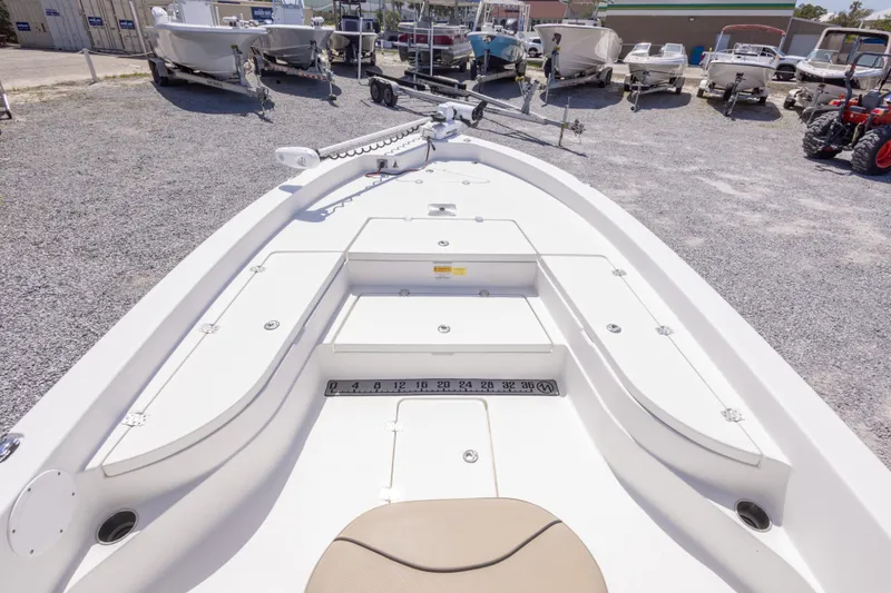 Slide: The Image of 2017 NauticStar 2400 Sport boat deck with storage compartments, parked among other boats. - 28